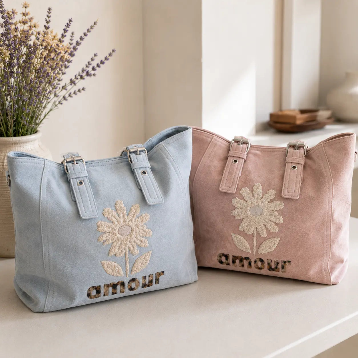 Sac cabas femme effet suédine avec fleur en relief et inscription Amour, disponible en bleu pastel et rose poudré, grande capacité avec multiples poches zippées.