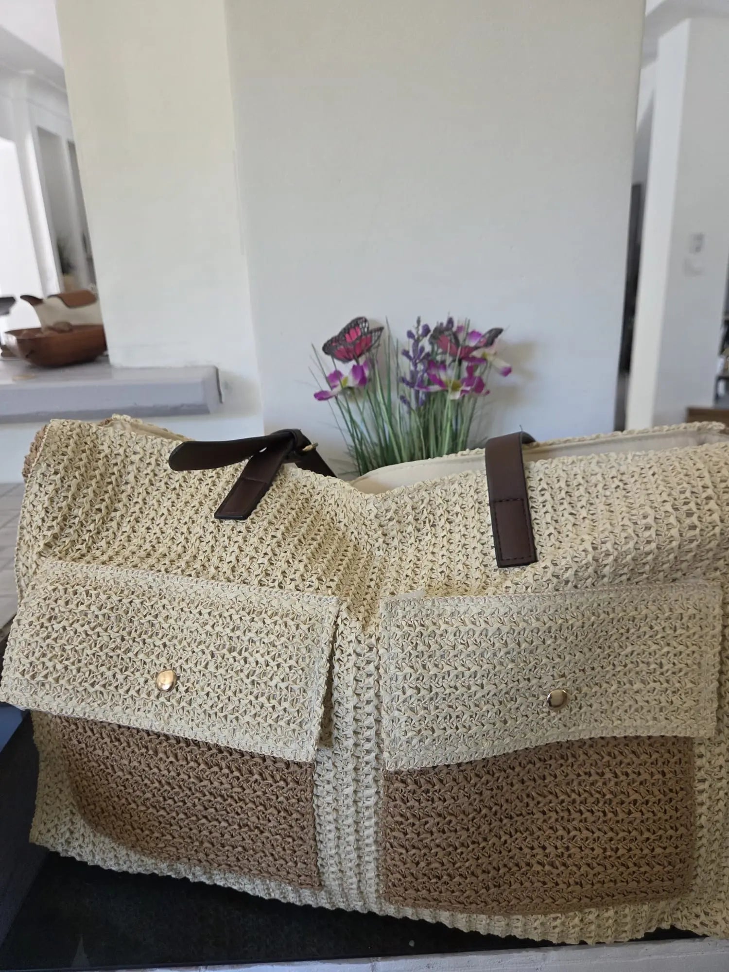 Grand sac cabas bohème en paille tressée avec fermeture zippée, deux poches avant et anses marron, style naturel chic pour l’été et la plage.