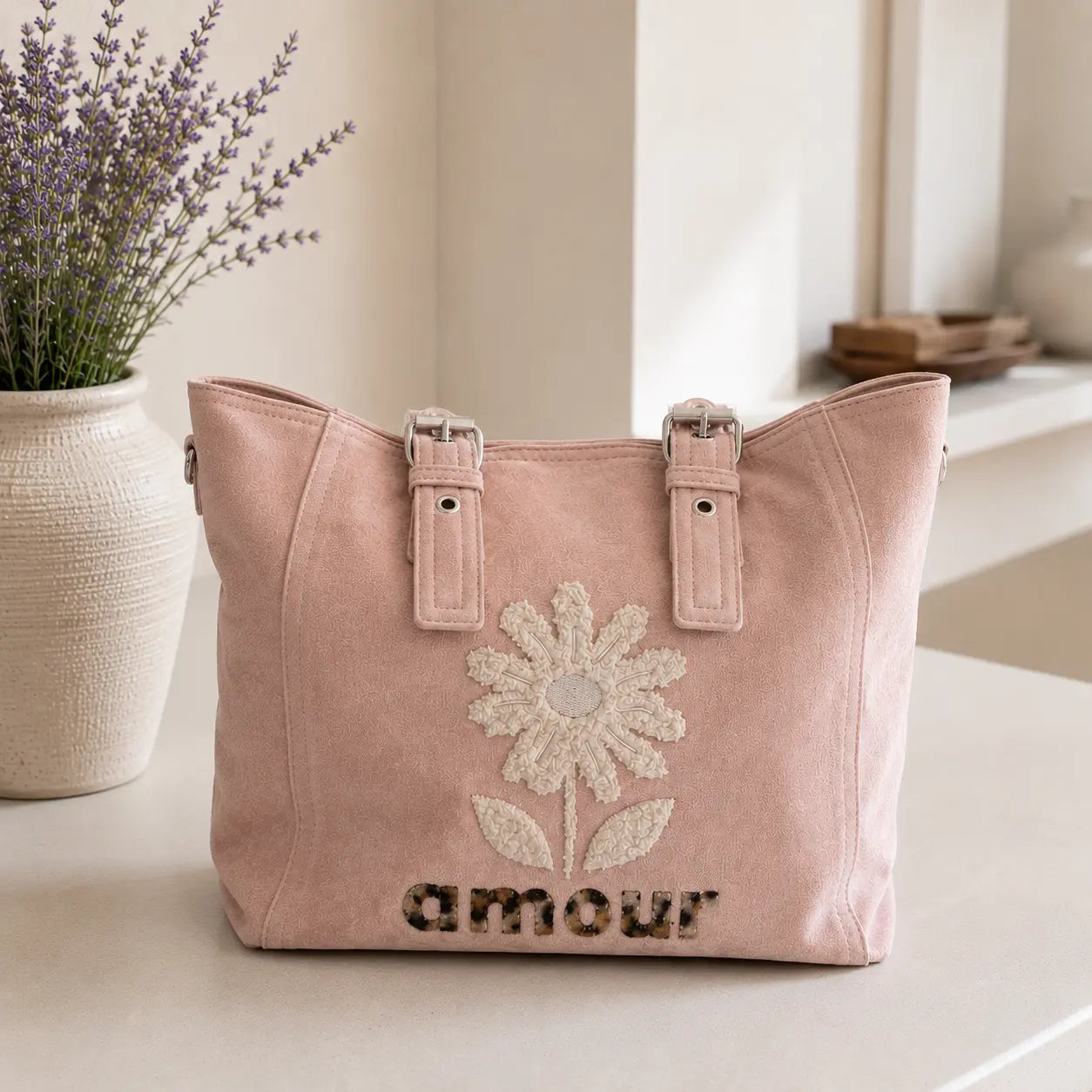 Sac cabas femme effet suédine avec fleur en relief et inscription Amour, disponible en bleu pastel et rose poudré, grande capacité avec multiples poches zippées.